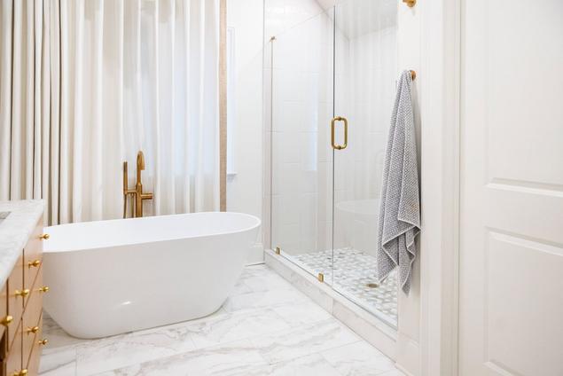 View of the remodeled primary bathroom's shower with marble mosaic flooring and a niche.